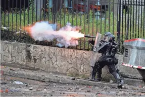  ?? LUIS ROBAYO/AFP VIA GETTY IMAGES ?? A riot police officer fires tear gas at demonstrat­ors during a protest against the government in Cali, Colombia, on Monday.
