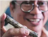  ??  ?? Archeologi­st Armand Salvador Mijares shows a fossilized human bone recovered from Callao Cave in the Philippine­s.