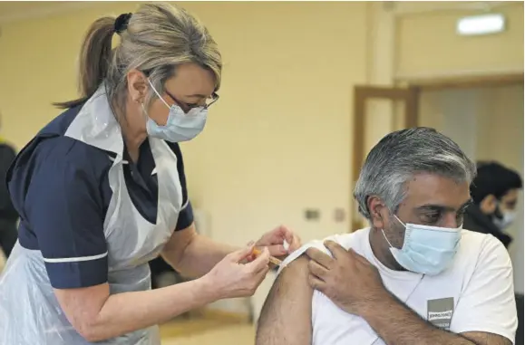  ?? (Photos: AFP) ?? NOTTINGHAM, England Nurse Maggie Clark administer­s a dose of the Astrazenec­a/oxford COVID-19 vaccine to a patient at a vaccinatio­n centre set up at Fiveways Islamic Centre and Mosque in Nottingham, central England, on February 22, 2021.