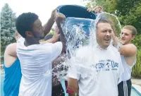  ?? ?? Dieruff High School linebacker Brian Sutton, left, gets help from teammates as they dump ice water over the head of head coach Kyle Beller as Beller takes the Ice Bucket Challenge to benefit ALS during a Dieruff alumni picnic at the home of John Hughes in Lower Saucon Township on Aug. 24, 2014.