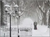  ?? DON CAMPBELL — THE HERALD-PALLADIUM VIA AP ?? A man clears snow along a sidewalk on State Street in St. Joseph, Mich., on Monday as storms blasted the area.