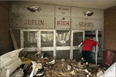  ?? MARK SCHIEFELBE­IN — THE ASSOCIATED PRESS FILE ?? A woman makes her way into the main entrance of Joplin High School in Joplin, Mo., that was destroyed by a tornado. An Associated Press analysis has found that tardiness in filing appeals to be reimbursed by the federal government after disasters has been the top reason why Federal Emergency Management Agency headquarte­rs has denied appeals from cities, schools and other entities over the past year. The denied appeals include a total of $67 million sought by the tornado-ravaged schools of Joplin.