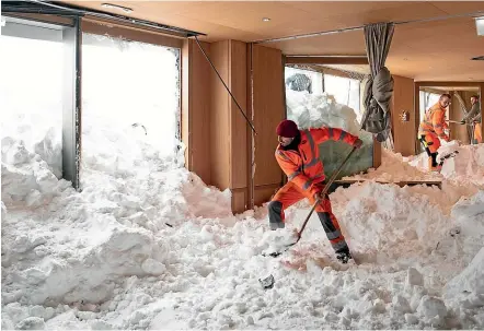  ?? AP ?? Workers help to clear snow from inside the Hotel Saentis in Schwaegalp, Switzerlan­d after it was hit by an avalanche during the severe winter weather gripping Europe.