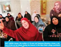  ?? — AFP ?? BAYT AWWA: Hanan, the mother of 18-year-old Badawee Masalma, shows a picture of him on her phone during his funeral in this West Bank village southwest of Hebron yesterday.