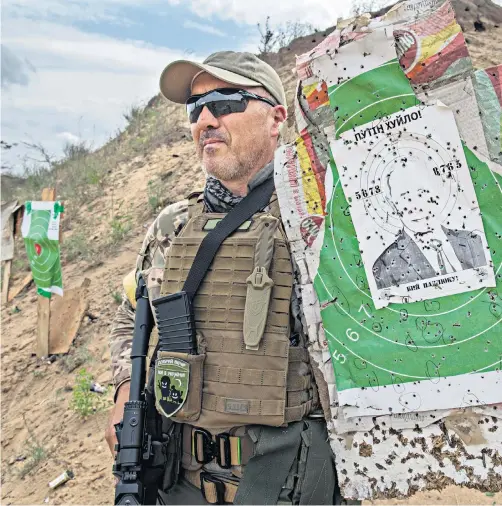  ?? ?? A member of the Kherson Brigade displays the paper target of Vladimir Putin, peppered with bullets