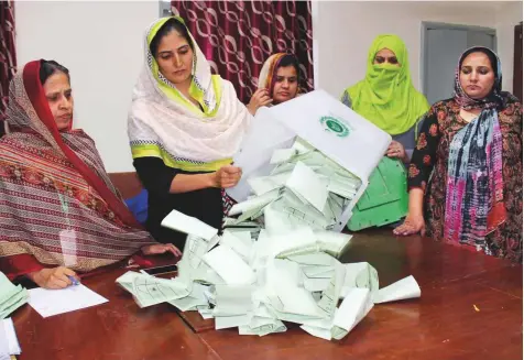  ?? Online ?? Polling staff empty the ballot boxes for counting of votes at a polling station after the by-elections. Despite announceme­nts through print and electronic media a low turnout — around 22pc in urban areas — marked yesterday’s by-elections.