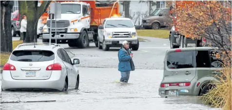  ?? JOHN RENNISON/ THE HAMILTON SPECTATOR ?? A man walks across a flooded portion of Grand River Avenue in Brantford this week after the Grand River flooded areas.