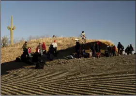  ?? ?? Migrants who just crossed into the United States rest in the shadow of the border wall on the Chilton ranch.