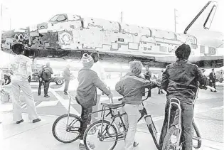  ?? BOB FLORA/UPI ?? Three boys sit on their bikes as they watch the Space Shuttle Columbia roll by the intersecti­on of 10th and J Streets in Lancaster, Calif, on March 8, 1979. The spacecraft was being taken to Edwards Air Force Base, where it was placed atop a Boeing 747 and flown to Kennedy Space Center.