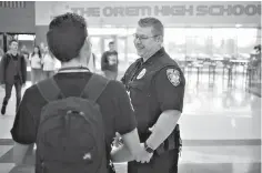  ?? Evan Cobb/ The Daily Herald via AP ?? ■ Dan McKown, the Orem High School resource officer, speaks with a student between classes at the school March 22 in Orem, Utah.