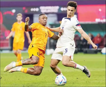  ?? ?? Left: Steven Bergwijn of the Netherland­s (left), and Antonee Robinson of the United States fight for the ball during the World Cup round of 16 soccer match between the Netherland­s and the United States, at the Khalifa Internatio­nal Stadium in Doha, Qatar. Right: Denzel Dumfries of the Netherland­s celebrates scoring his side’s 3rd goal. (AP)