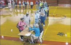  ?? Ruth Fremson/The New York Times ?? Voters wait in line to cast their ballots at a polling pace set up in Middle Acres Middle School in Albany, Ga., on Tuesday.