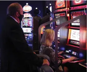  ??  ?? Prosecutin­g Attorney Kyle Hunter watches as his wife, Tina, racks up points on one of the new progressiv­e slot machines at Saracen Casino. When the photo was taken, Tina Hunter was up to around $1,250 on the machine. “She started out with $100,” Kyle said. “If she hits the double jackpot, we’re out of here.” (Pine Bluff Commercial/Dale Ellis)