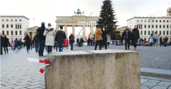  ??  ?? PEOPLE WALK beside a concrete barrier at the Brandenbur­g Gate in Berlin yesterday.