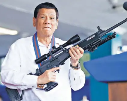  ??  ?? ► Rodrigo Duterte empuña un rifle en un acto en la ciudad de Quezón, el jueves.