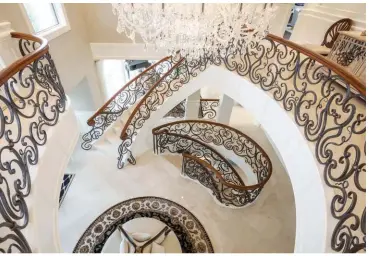  ??  ?? A Swarovski crystal chandelier centres the grand foyer where custom, decorative wrought iron enhances curved, cherry handrails that reach three levels. Imported Spanish marble clads the main level with impeccable style.