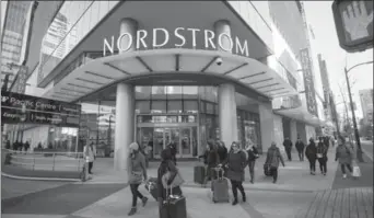  ?? BEN NELMS, BLOOMBERG ?? Pedestrian­s walk past a Nordstrom store in downtown Vancouver. Nordstrom and other luxury retailers have been expanding in Canada at the same time as department store chains have been shrinking.