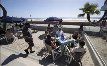  ?? AP PHOTO/GREGORY BULL ?? People sit at tables at the Beach House Grill Thursday, in San Diego. San Diego County began to relax some rules regarding social distancing and efforts to slow the spread of the new coronaviru­s Thursday, as restaurant workers scrambled to prepare for limited indoor dining.