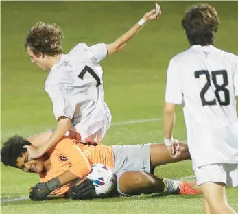  ?? STEPHEN M. DOWELL/ORLANDO SENTINEL ?? Bishop Moore’s Jace Overturf falls on Gulliver Prep keeper Luis Boschetti during the FHSAA Class 4A boys soccer state championsh­ip game at Spec Martin Stadium in DeLand on Thursday night.