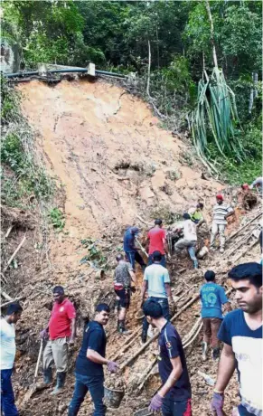  ??  ?? Team effort: Penang Hill Corporatio­n workers and hill residents clearing some of the earth on the funicular railway track.