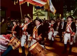  ?? NATHAN KLIMA FOR THE BOSTON GLOBE ?? A pipe and drums corps led a crowd to Atlantic Wharf in downton Boston ahead of the reenactmen­t Saturday night that marked the 250th anniversar­y of the Boston Tea Party.