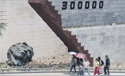  ?? CHINAFOTOP­RESS / GETTY ?? 300.000 muertos. Unos turistas, en el monumento que conmemora la masacre de Nankín. China cuantifica en 300.000 las víctimas mortales de la violencia de las tropas
japonesas en la ciudad, aunque los estudiosos extran
jeros la rebajan a 42.000