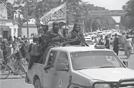  ?? RAHMAT GUL/AP ?? Taliban fighters display their flag Thursday as they patrol in Kabul, Afghanista­n.