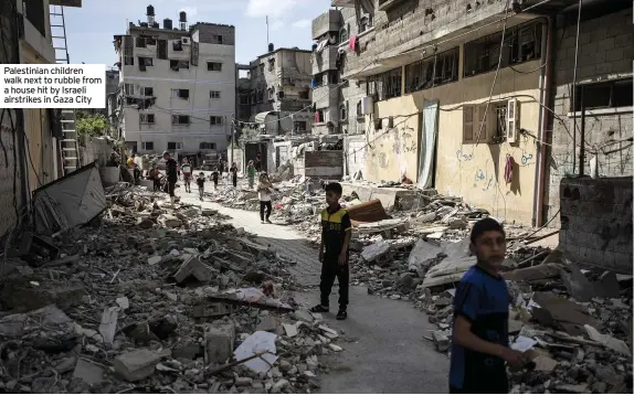  ??  ?? Palestinia­n children walk next to rubble from a house hit by Israeli airstrikes in Gaza City