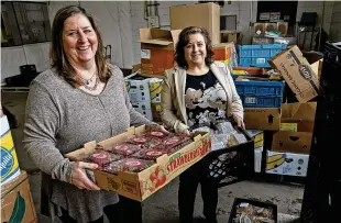  ?? ?? Two new hires at the Second Harvest Food Bank, Toni Tayloe-haddix (left) and Jennifer Brunner, help at distributi­on Friday. The positions were funded through a grant from Feeding America.