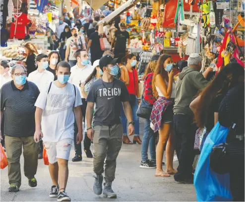 ?? JACK GUEZ / AFP via Gett y Images files ?? Shoppers wearing protective masks walk through the Carmel market in Tel Aviv last week as markets and shopping
malls reopened in Israel after being closed for more than a month to prevent the spread of coronaviru­s.