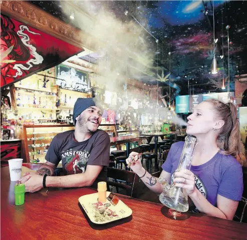  ?? JEFF VINNICK / GETTY IMAGES ?? Patrons smoke marijuana with a bong Wednesday at the New Amsterdam Cafe in Vancouver as the federal government announces recreation­al pot will be legalized as of Oct. 17 in Canada