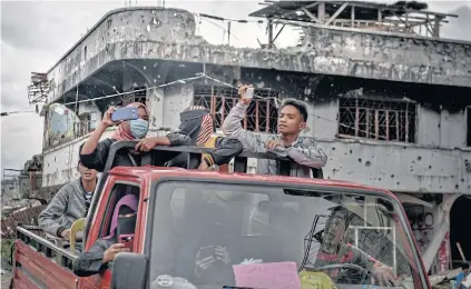  ??  ?? LOOK WHAT THEY DID: Left, residents document the wreckage during a brief return to Marawi, in the southern Philippine­s, this month.