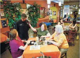  ??  ?? ABOVE: Ahmed Obo, Jambo’s chef and owner, meets with regulars Maureen McCarthy, Sharon Starkey and Debbie Birkhauser during lunch Tuesday afternoon.