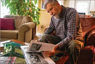  ?? STEVE MELLON PHOTOS / POST-GAZETTE ?? John Cleary, who was wounded by Ohio National Guardsman while a student at Kent State University in May 1970, examines a book of photograph­s of the historic shootings at the Ohio campus while at his Gibsonia home in 2019. Cleary, a retired architect, had noticed a crowd near Blanket Hill after he got out of class that day. Intrigued, the 19-year-old freshman from Scotia, N.Y., stopped to take pictures. His photograph­y ended when a guardsman’s bullet slammed into his chest.