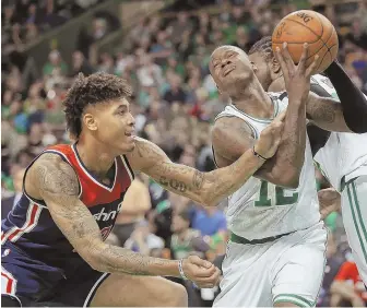 ?? STAFF PHOTO BY NANCY LANE ?? GRIPPING STORY: The Celtics’ Terry Rozier takes a slap on the arm from Kelly Oubre Jr. of the Wizards during yesterday’s playoff game at the Garden.