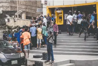  ?? BENSON IBEABUCHI/GETTY IMAGES ?? People wait in front of a bank in Lagos, Nigeria, hoping to withdraw naira notes. The country’s central bank is withdrawin­g notes from circulatio­n, partly in an effort to cut down on counterfei­ting.