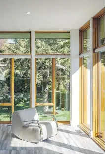  ?? DOUBLESPAC­E PHOTOGRAPH­Y ?? Large windows help integrate the interior and exterior, while discreet roller blinds provide privacy when needed in the sitting room of the mid-centuryins­pired Massey House, by Art House Developmen­ts. The painted drywall between the stained pine frames gives the windows a clean, defined look. ‘If we’d clad them just in pine, they would have looked too heavy and cottagey,’ says Art House president Alex Diaz.