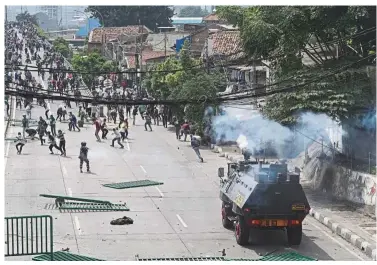  ??  ?? Venting frustratio­ns: Demonstrat­ors run as a police armored vehicle drives towards them during a protest in Jakarta. — Bloomberg