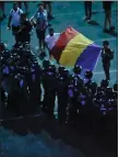  ??  ?? „ Demonstrat­ors hold a Romanian flag in front of police in Bucharest.