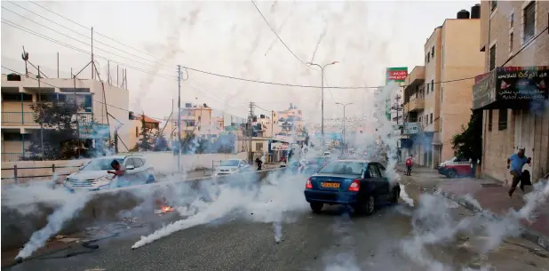  ?? AFP ?? Palestinia­n men run for cover from teargas during clashes between demonstrat­ors and Israeli security forces at the Qalandiya checkpoint between Ramallah and Jerusalem. —