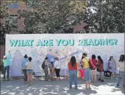  ?? Katie Falkenberg Los Angeles Times ?? FESTIVAL OF BOOKS attendees write what they are reading on a giant banner displayed at USC.