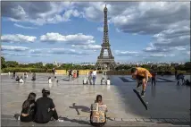  ?? MICHEL EULER/ AP ?? People hang out near the Eiffel Tower in Paris in late May. Americans are not likely to be allowed into Europe once the European Union lifts coronaviru­s-linked restrictio­ns because new infections are surging in the United States, among other reasons.