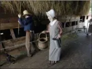  ?? STEVEN SENNE — THE ASSOCIATED PRESS ?? In this Wednesday photo, reenactors in the roles of 1830s farm workers carry milk buckets and pitchers in a barn at Old Sturbridge Village, in Sturbridge, Mass. With a $75,000grant from the National Endowment for the Humanities, Old Sturbridge Village, a living history museum that depicts life in a small New England town in the 1830s, is taking a deep look at the way it presents the past, including the roles of minorities and women, in an effort to stay relevant to a