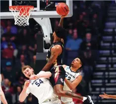  ?? (Reuters) ?? FLORIDA STATE Forward Phil Cofer (with ball) goes hard to the hoop against Xavier defenders Sean O’Mara (54) and forward Kaiser Gates during the second half of the No. 9 Seminoles’ 75-70 upset victory of the No. 1 Musketeers in Sunday’s West Region...