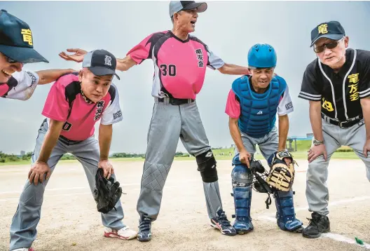  ?? SHIHO FUKADA/THE NEW YORK TIMES PHOTOS ?? Yuji Ryuzaki, center, with players on the Ryuyukai softball team last July. Ryuzaki started the team in 2012 to help former yakuza build new lives.