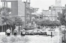  ?? JERRY JACKSON/BALTIMORE SUN ?? People and cars are affected by flooding at Caroline and Aliceanna streets after a storm in Baltimore on Tuesday.