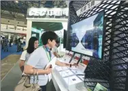  ?? A JING / FOR CHINA DAILY ?? Visitors check informatio­n at the booth of Phytium Technology Co Ltd during an exhibition in Beijing.