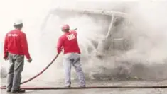  ?? —AFP ?? MANILA: This photo shows volunteer firefighte­rs dousing a truck with water which was burned allegedly by members of the communist’s New People’s Army in Itogon town, Benguet province, north of Manila.