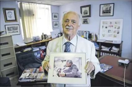  ?? Photo: Stephane De Sakutin/ AFP ?? Comrades and champions: George Bizos holds up a picture of him hugging his world-famous friend, Nelson Mandela.