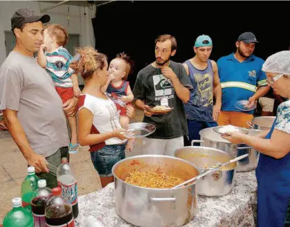  ?? Luiz Carlos Murauskas/Folhapress ?? Desabrigad­os recebem comida em centro cultural de Franco da Rocha (Grande SP), cidade afetadas pelo temporal da última semana que deixou 25 mortos no Estado; no município, 210 casas foram interditad­as